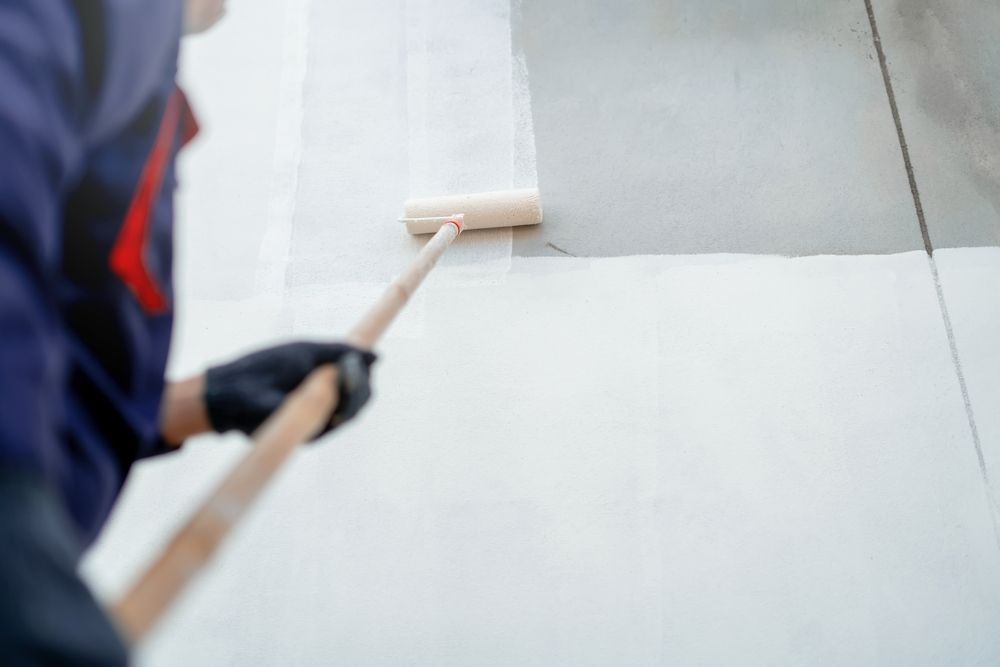 A Person Painting a Floor White with A Roller — Commercial Asset Maintenance In North Lakes, QLD