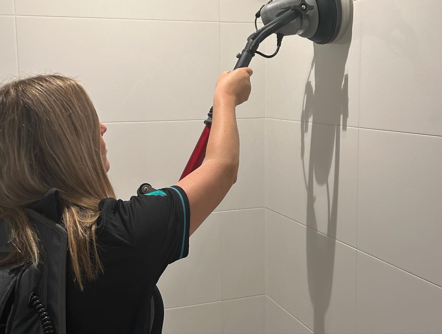 A Woman Using a Sander on Tiled Wall — Commercial Asset Maintenance In Redcliffe, QLD