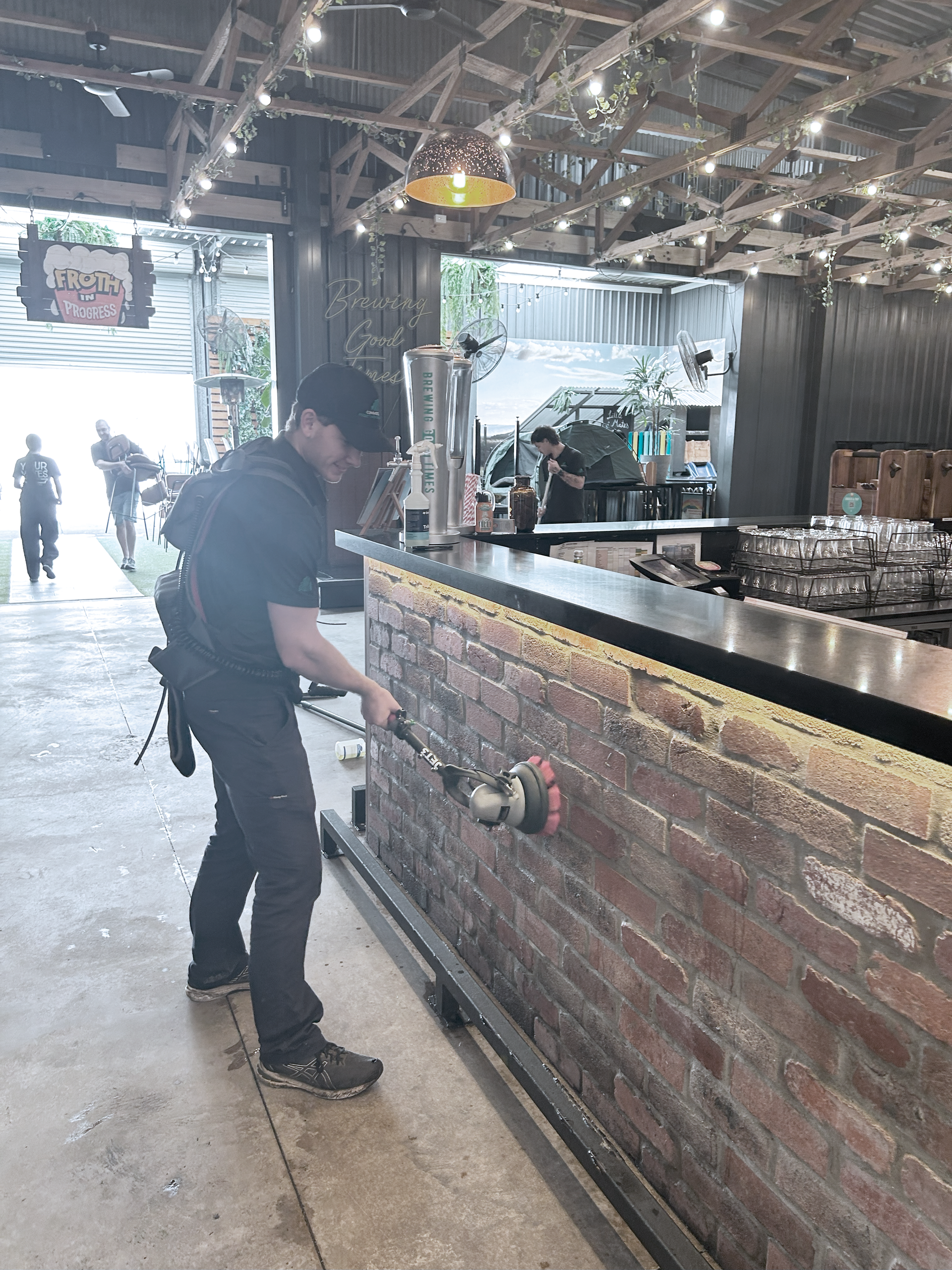 A Man Cleaning Brick Wall with A Brush — Commercial Asset Maintenance In Logan, QLD