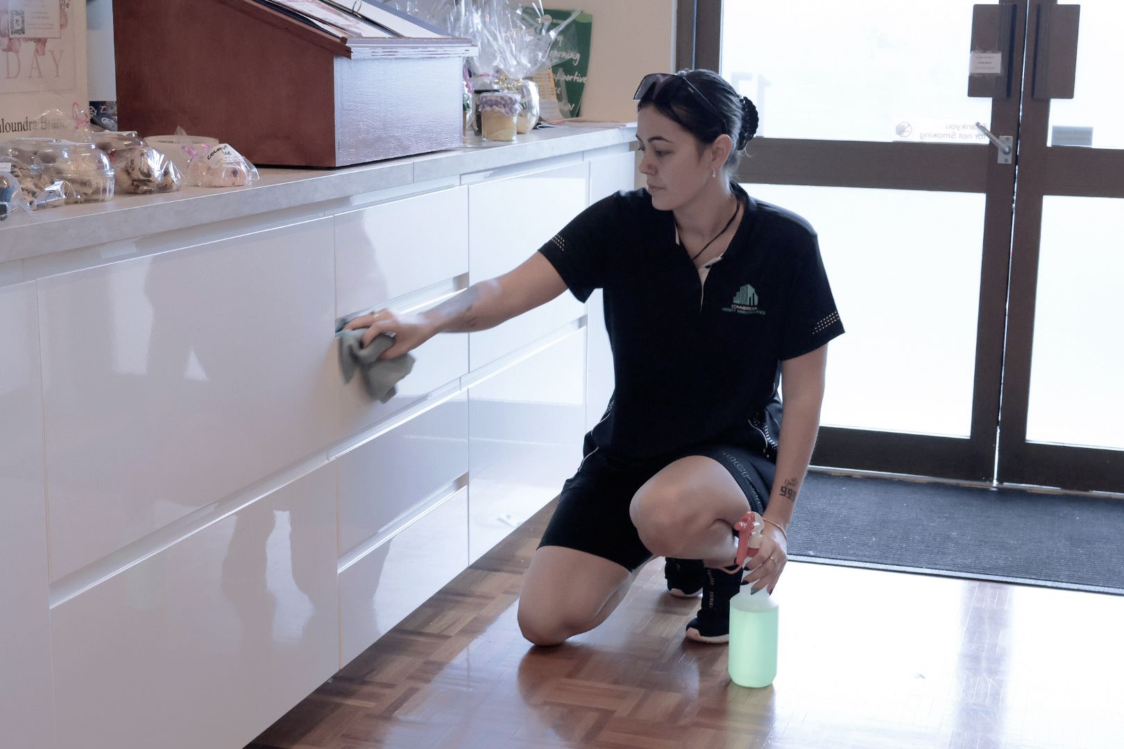 A Woman Cleaning White Cabinet in A Cafe — Commercial Asset Maintenance In Noosa, QLD