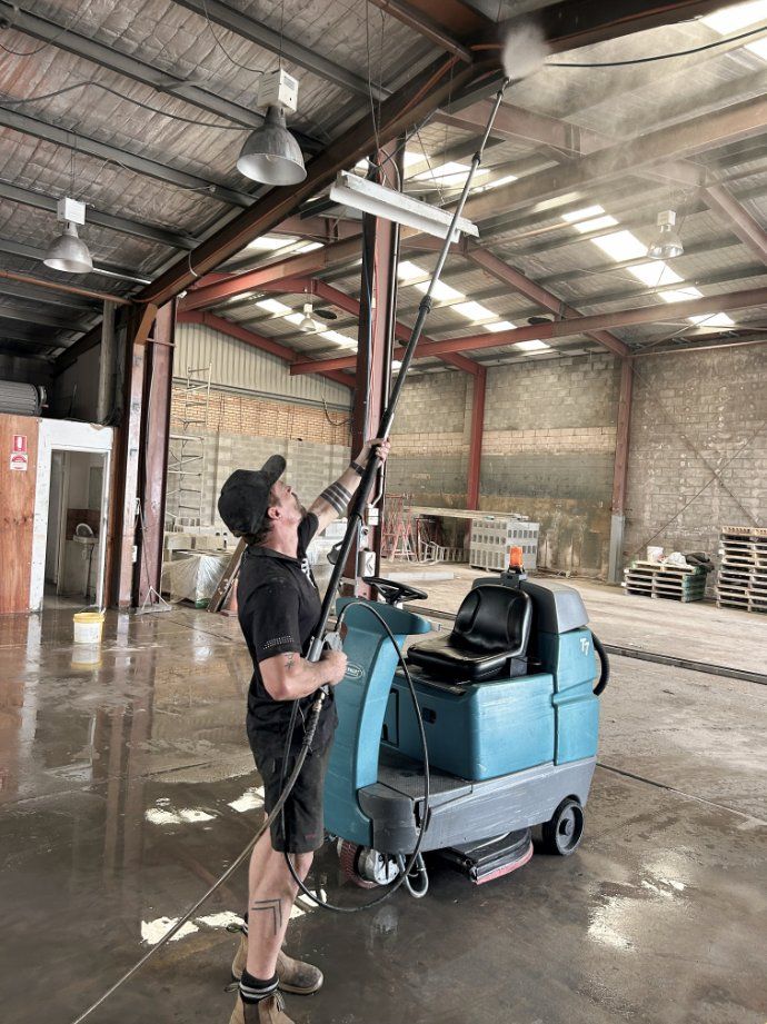 A Man is Cleaning a Tiled Floor With a Yellow Machine — Commercial Asset Maintenance In Beerwah, QLD