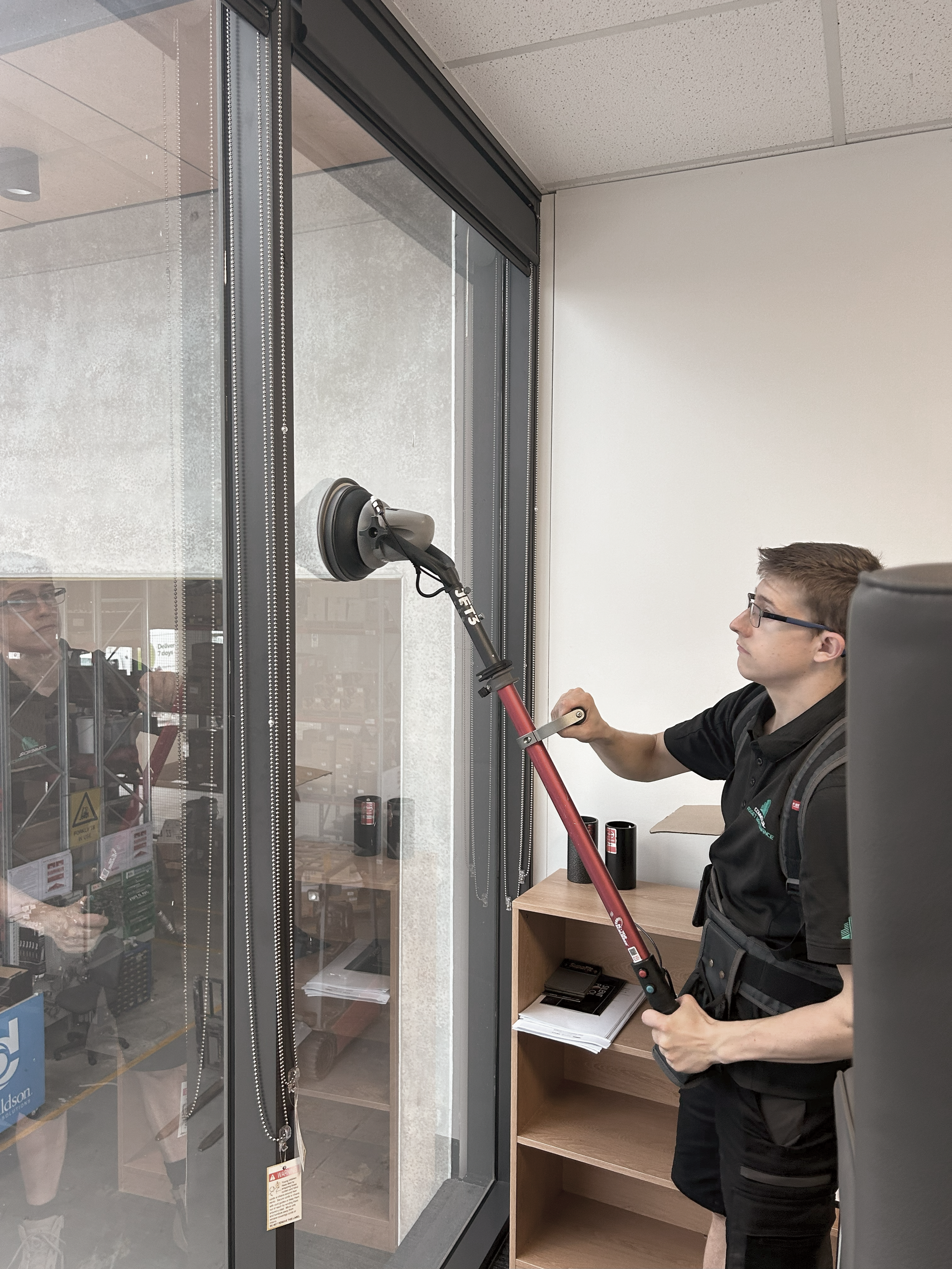 A Person Cleaning a Glass Window  — Commercial Asset Maintenance In Morayfield, QLD