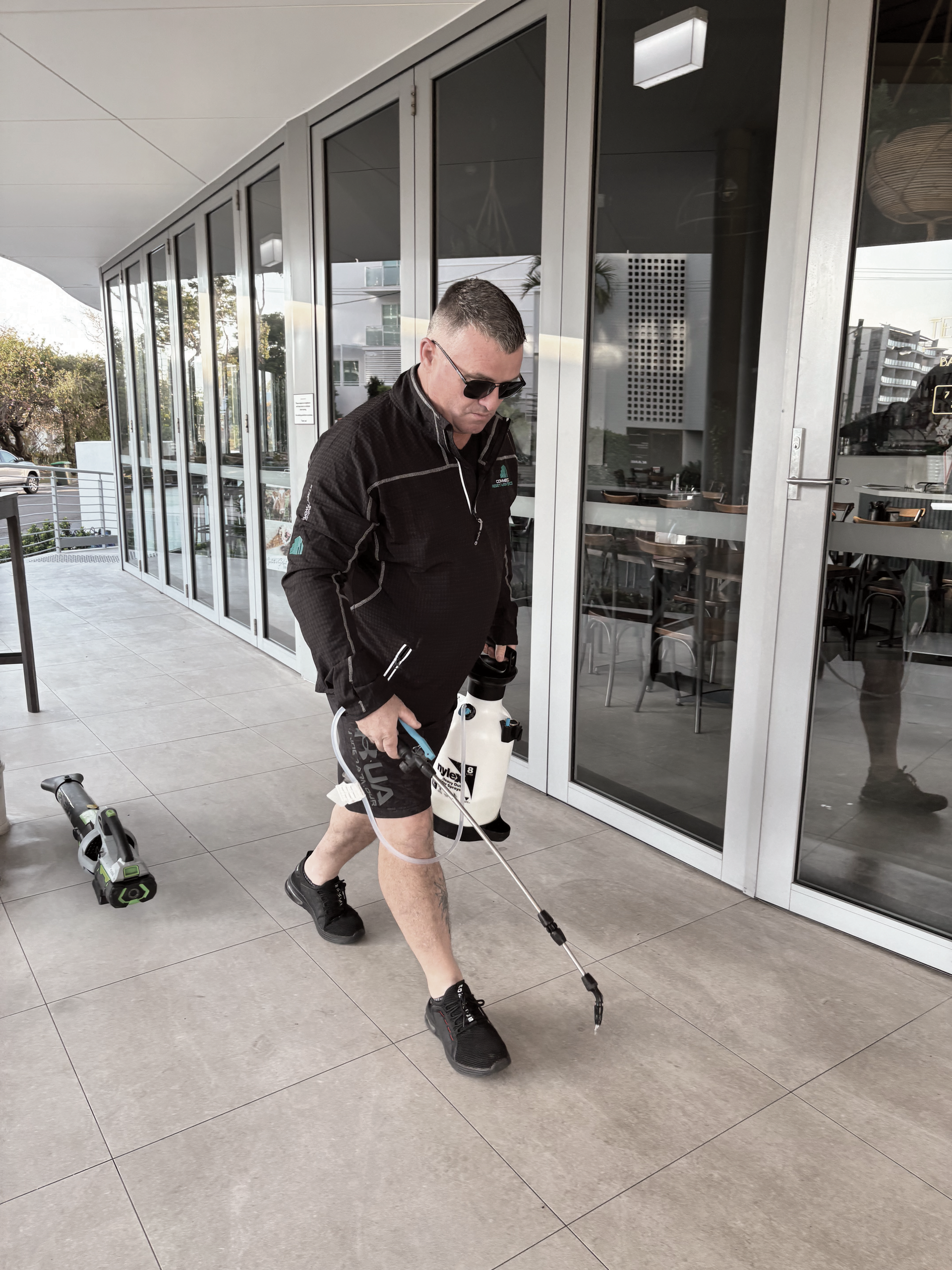 A Man with Sunglasses and White Cane Walks on A Patio — Commercial Asset Maintenance In Nambour, QLD
