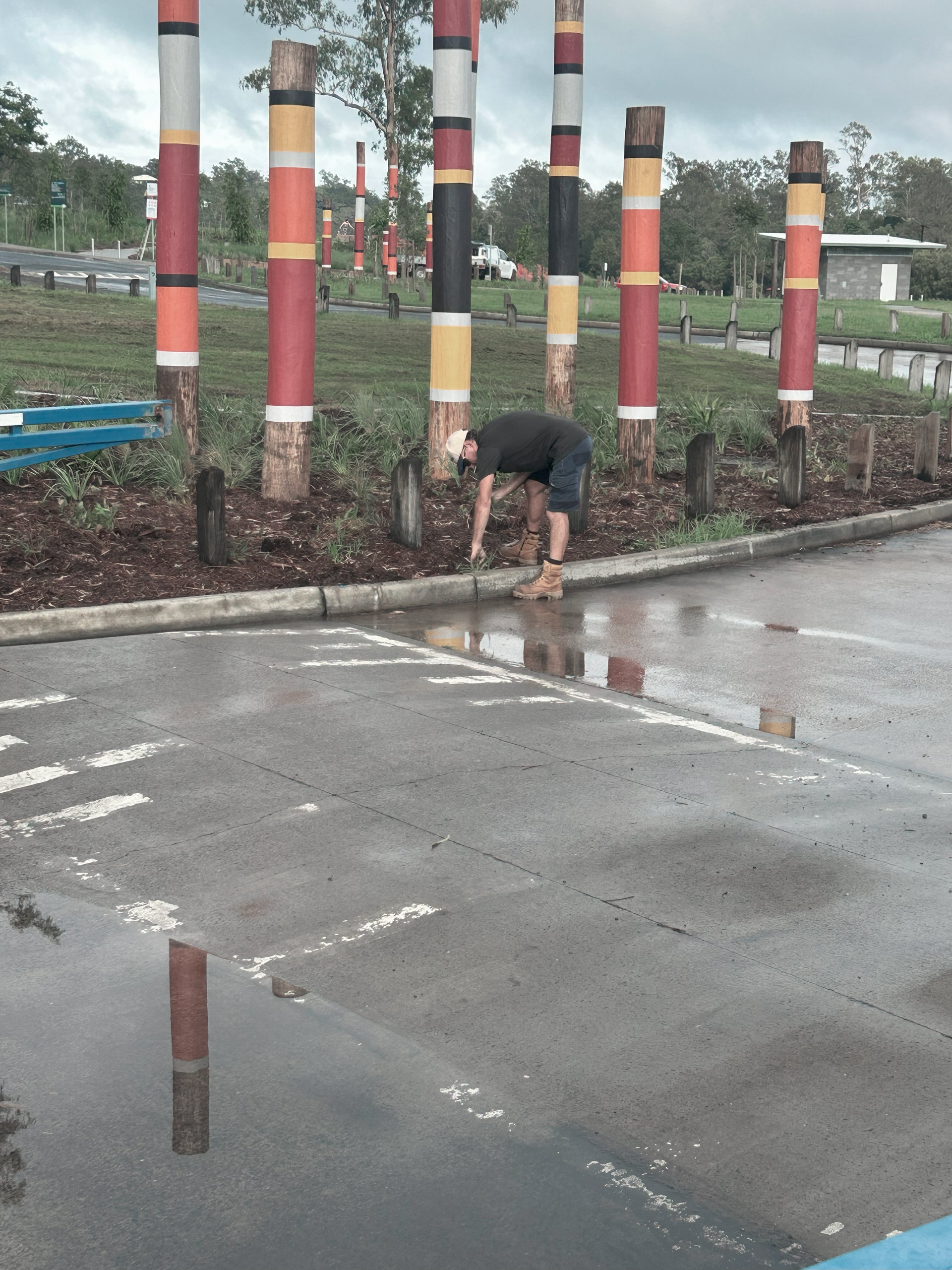 A Man is Standing Next to a Wall Holding a Hedge Trimmer — Commercial Asset Maintenance In North Lakes, QLD