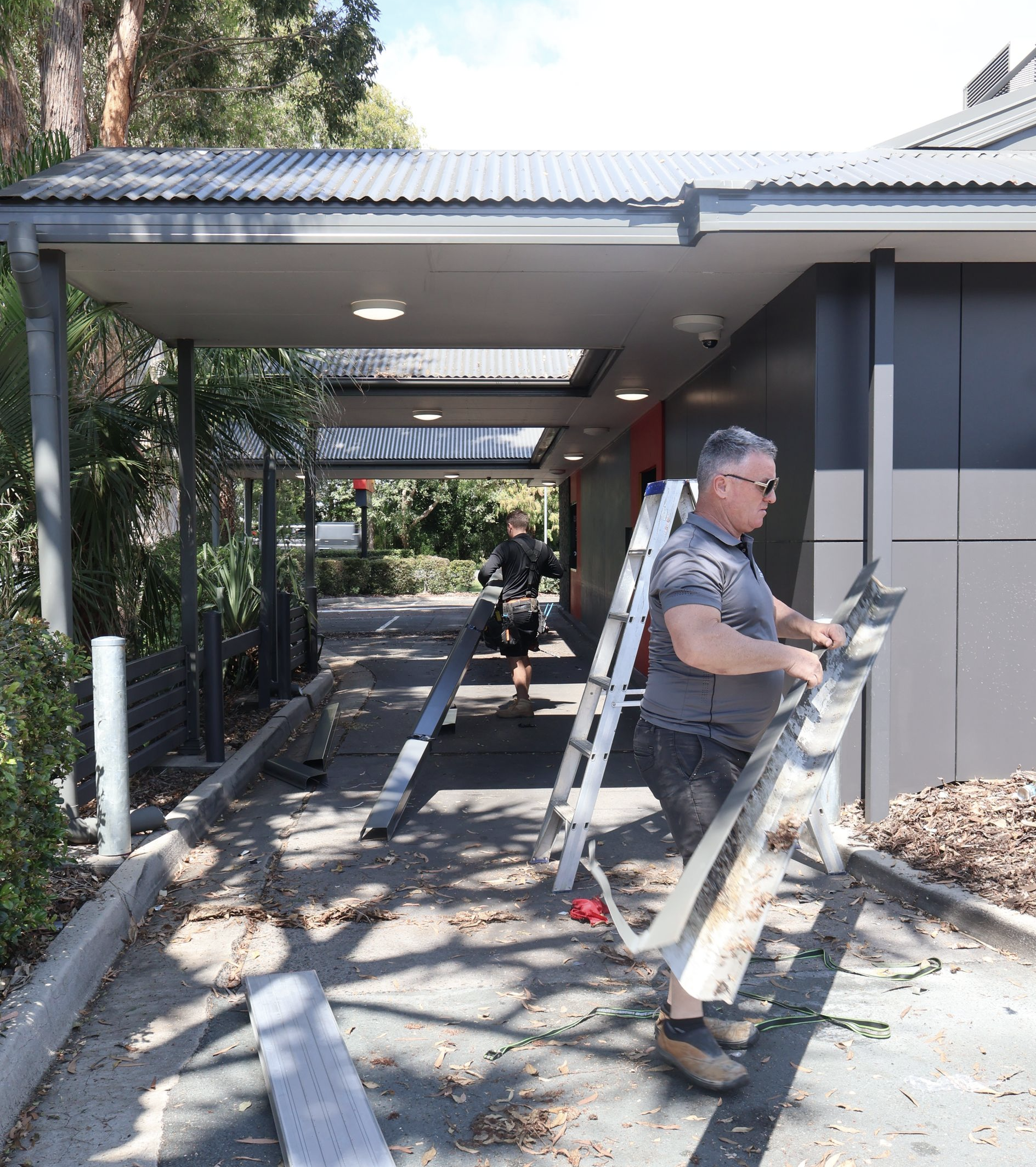 Two Men Cleaning Gutters at A Building Entrance — Commercial Asset Maintenance In Gold Coast, QLD