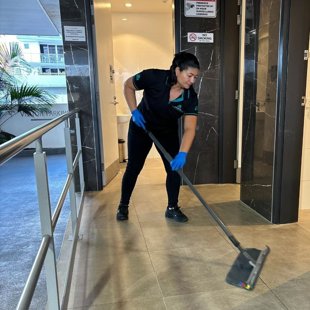 A Woman Cleans a Hallway with A Floor Sweeper — Commercial Asset Maintenance In Coolum Beach, QLD