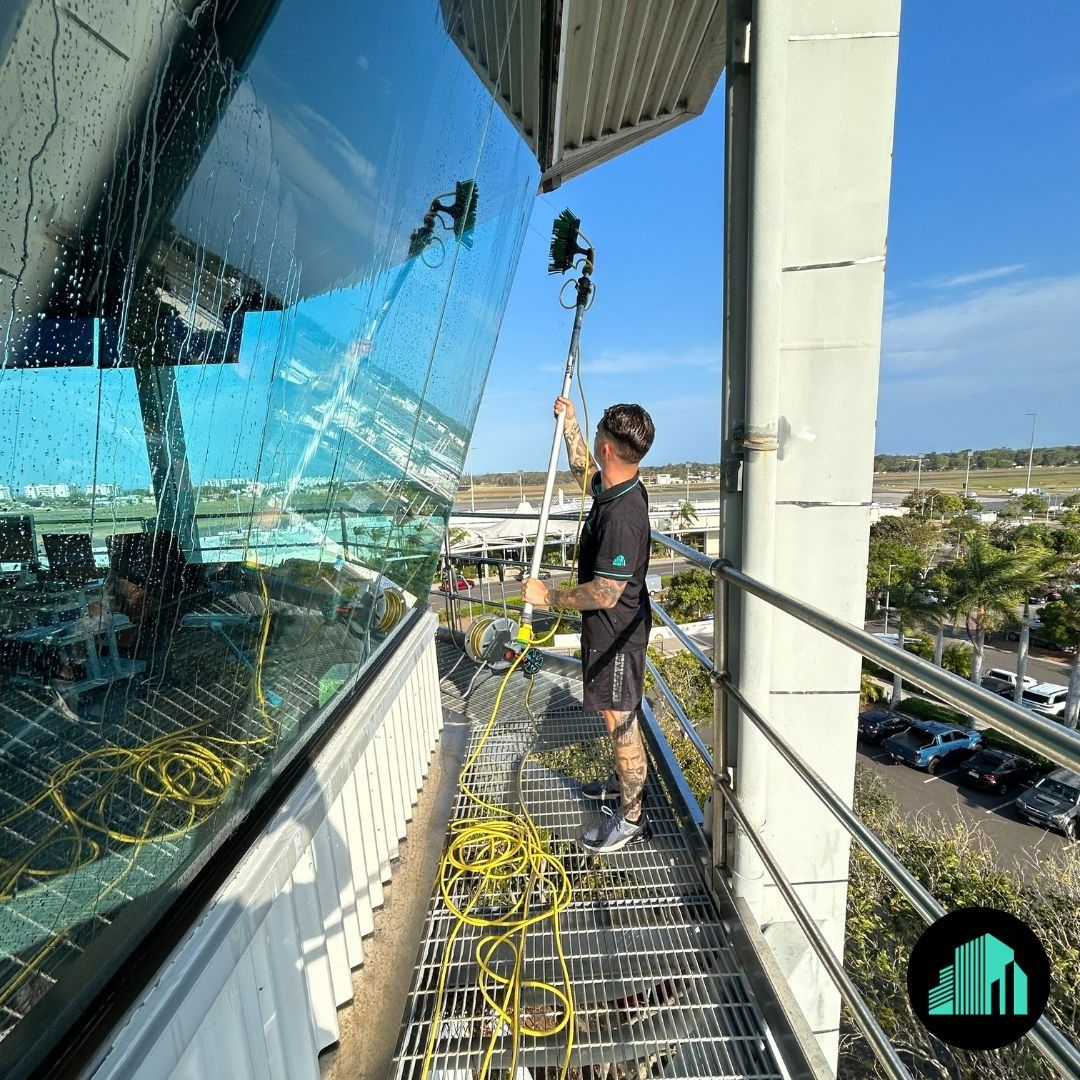 A Man Cleaning Large Windows with A Pole — Commercial Asset Maintenance In Gold Coast, QLD