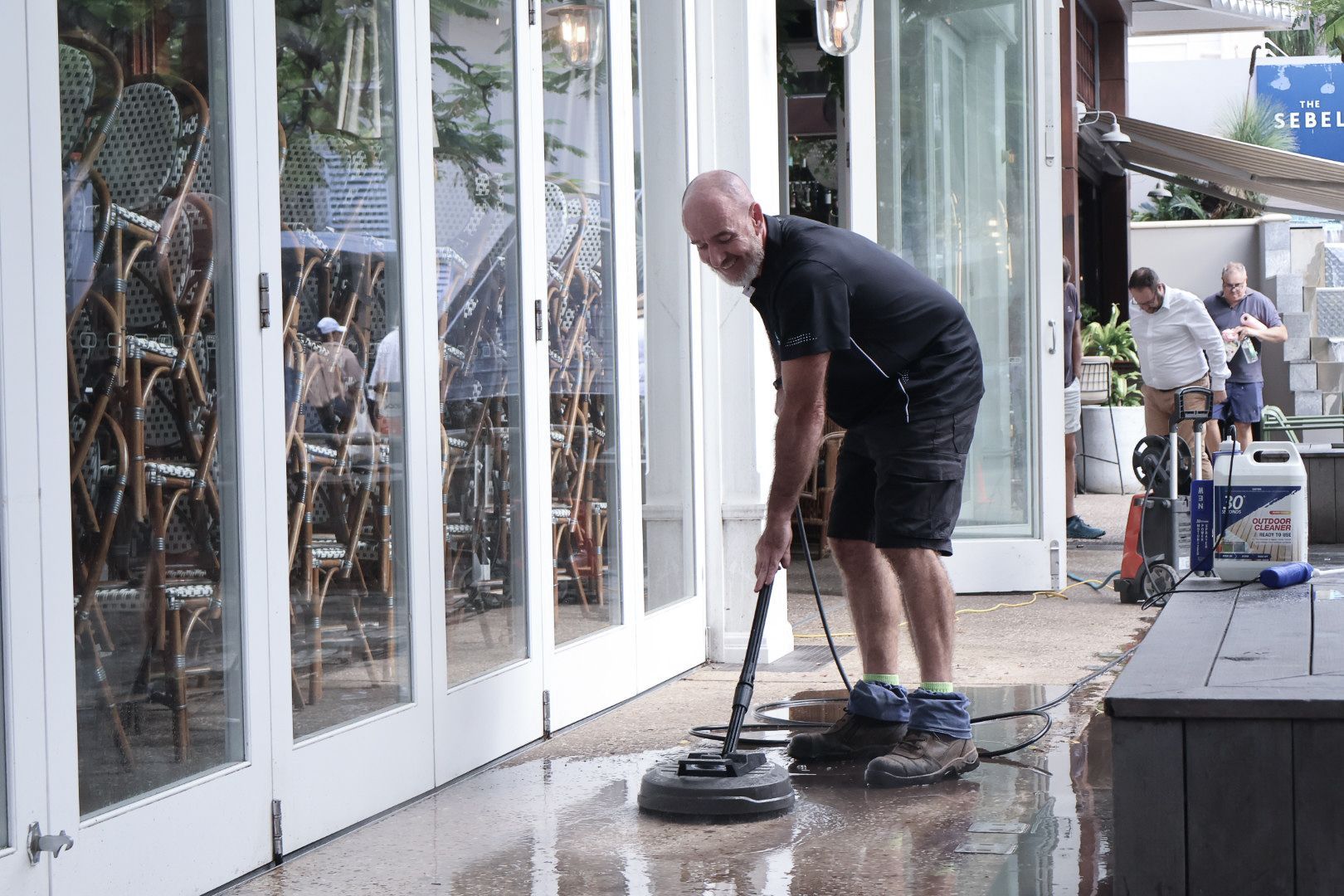 A Man Washing the Sidewalk in Front of A Building — Commercial Asset Maintenance In Strathpine, QLD