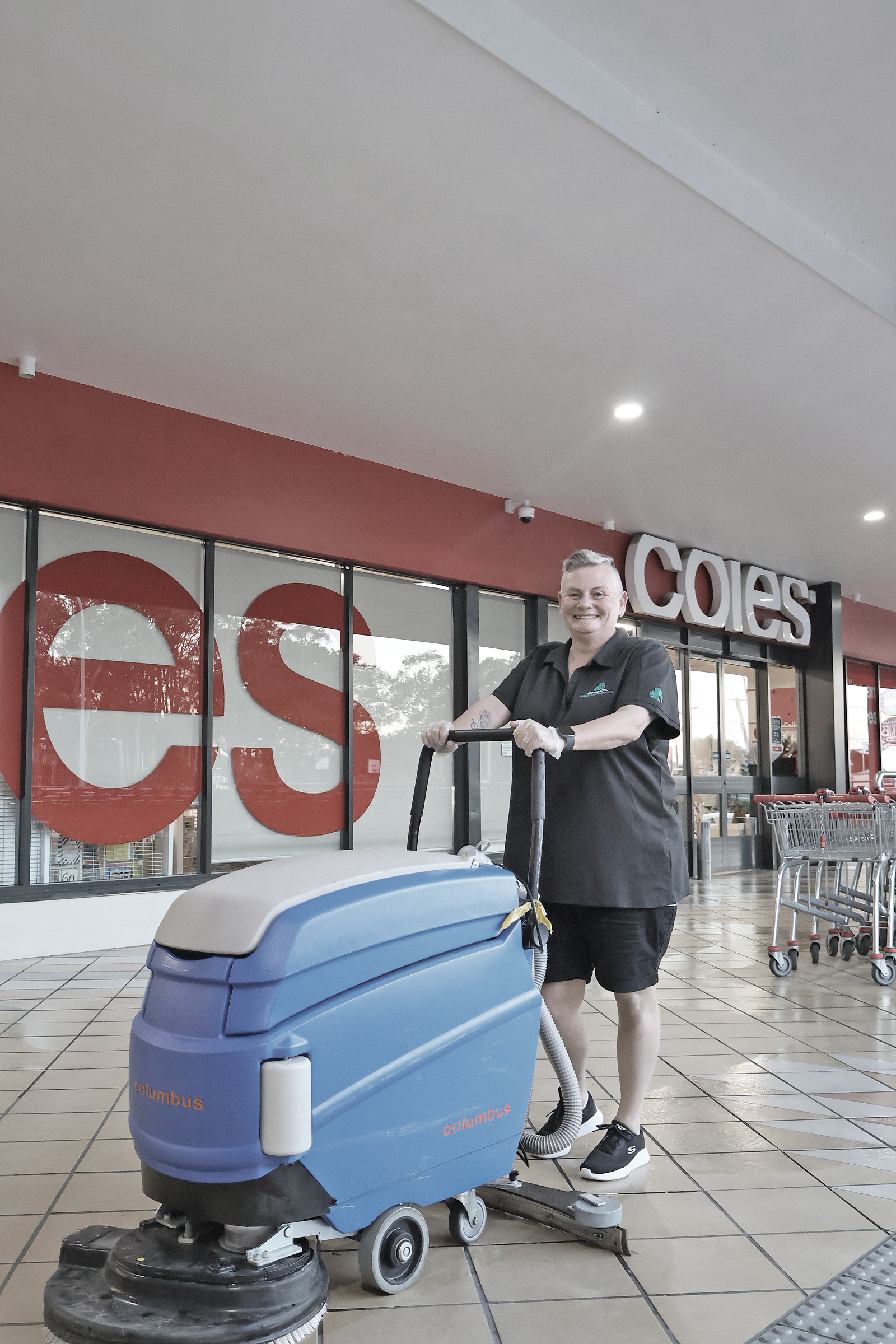 Person operating a blue floor cleaner in front of a Coles supermarket. — Commercial Asset Maintenance In 1Gympie, QLD
