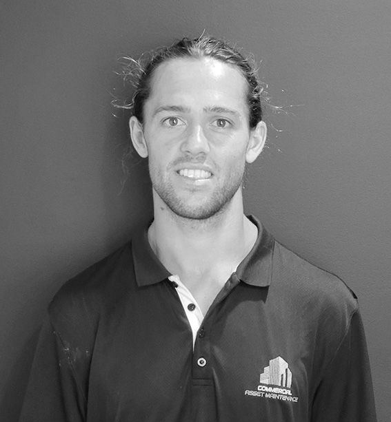 Man with long hair in a polo shirt smiles; logo on shirt reads