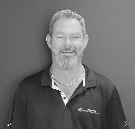 Man with a beard smiling, wearing a dark polo shirt and silver chain. — Commercial Asset Maintenance In 1Gympie, QLD