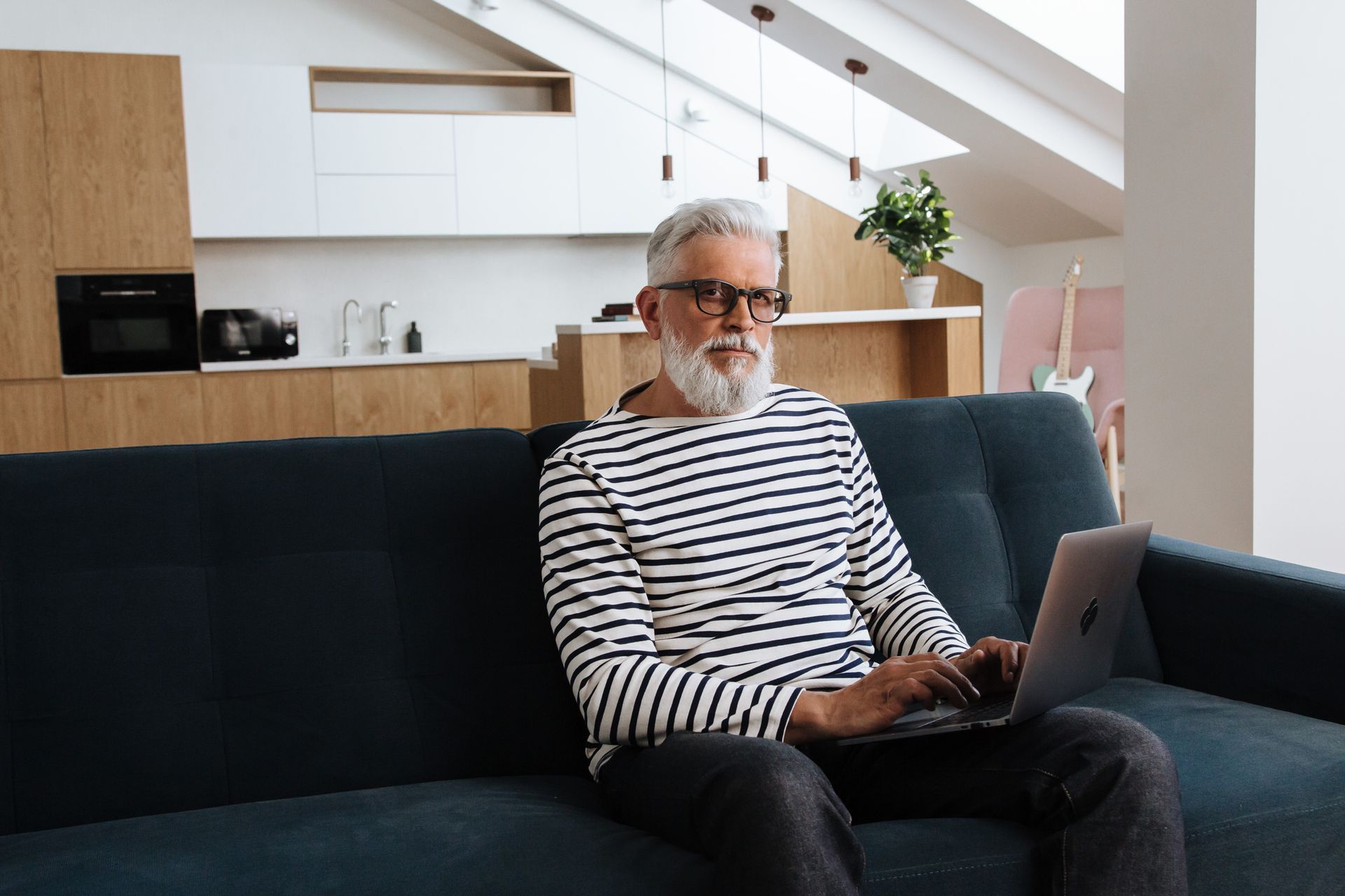 Retired man working on a laptop from his living room couch