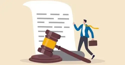 A man with a briefcase is standing next to a judge 's gavel and a large piece of paper.