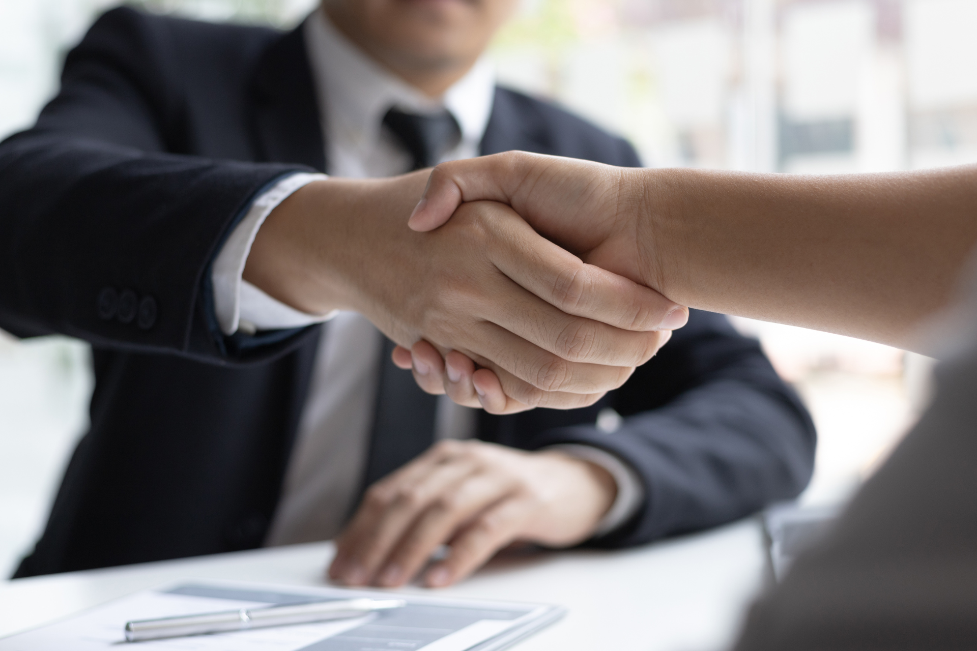 A man in a suit and tie is shaking hands with a woman.