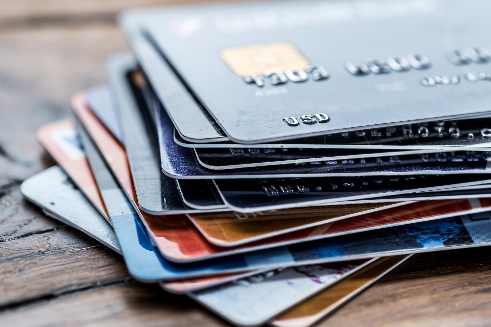 A stack of credit cards on a wooden table.