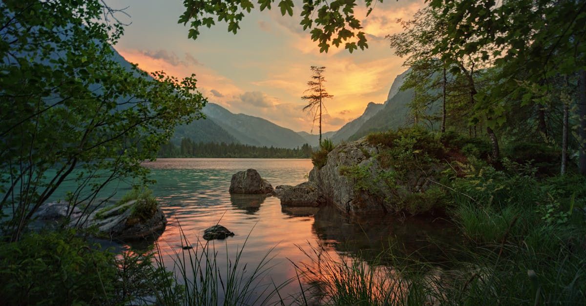 A lake surrounded by trees and mountains at sunset.