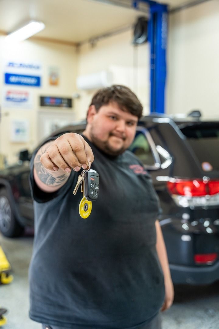 Man in garage holding keys in front of a black SUV.