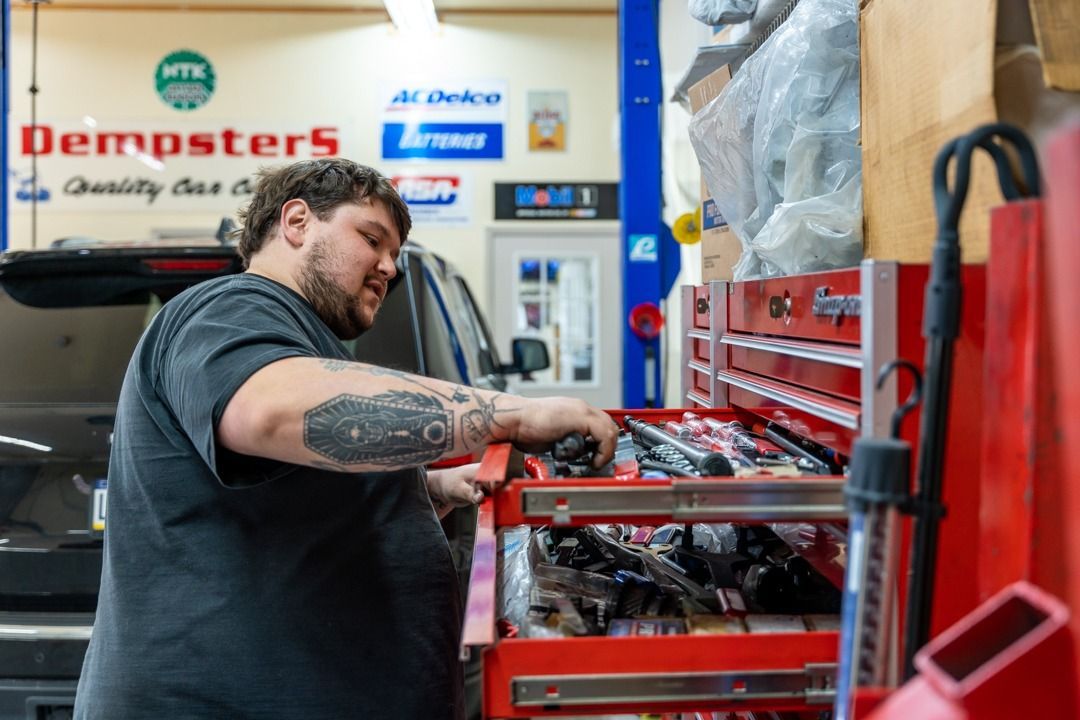 Mechanic at a garage reaching into a red toolbox for a tool.