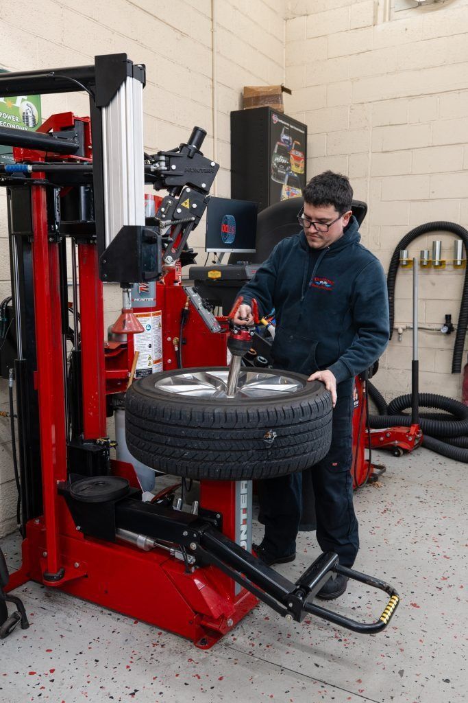 Mechanic using tire changer machine in a garage.