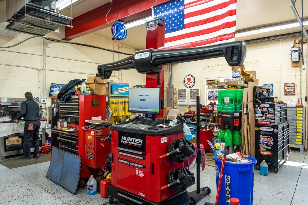 Wheel alignment machine in a car repair shop with an American flag.