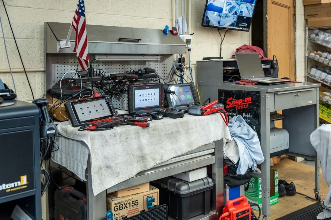 A cluttered mechanic's workbench with diagnostic equipment, tools, and an American flag.