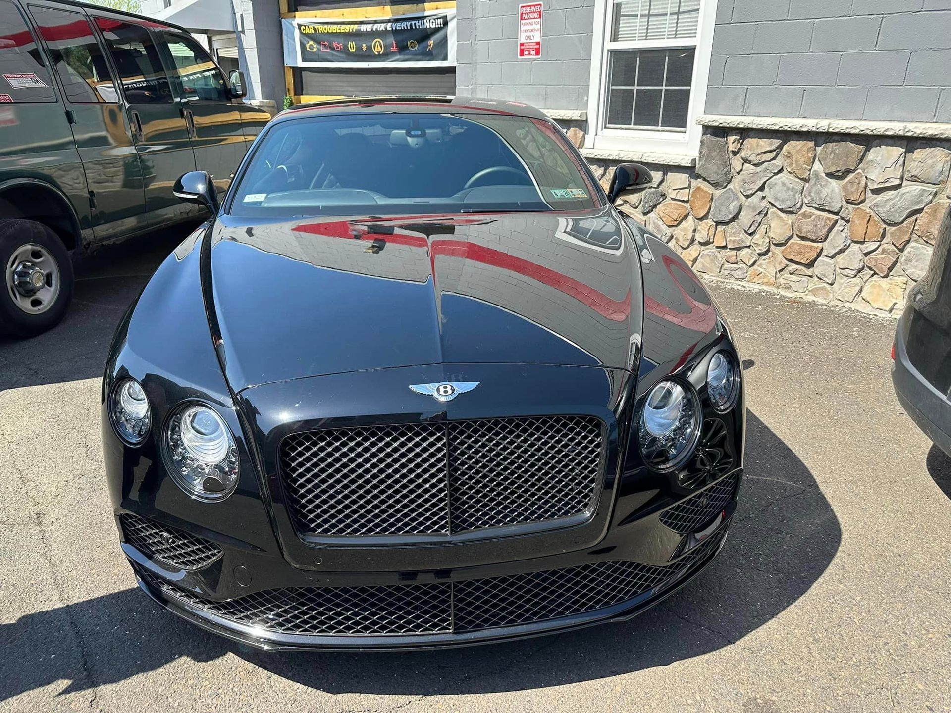 Black Bentley car parked in front of a building.