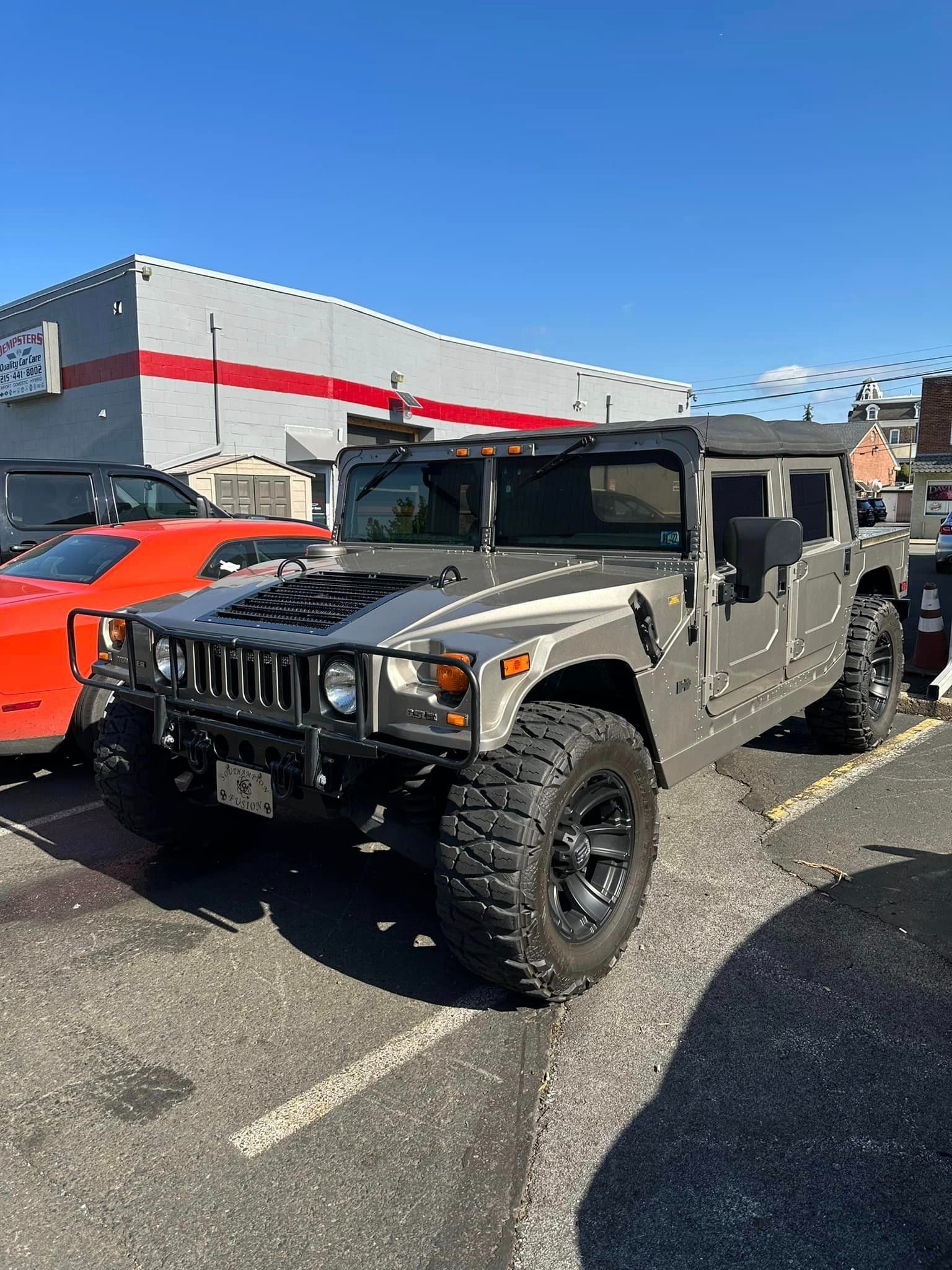 Gray Hummer H2 parked in a parking lot on a sunny day.