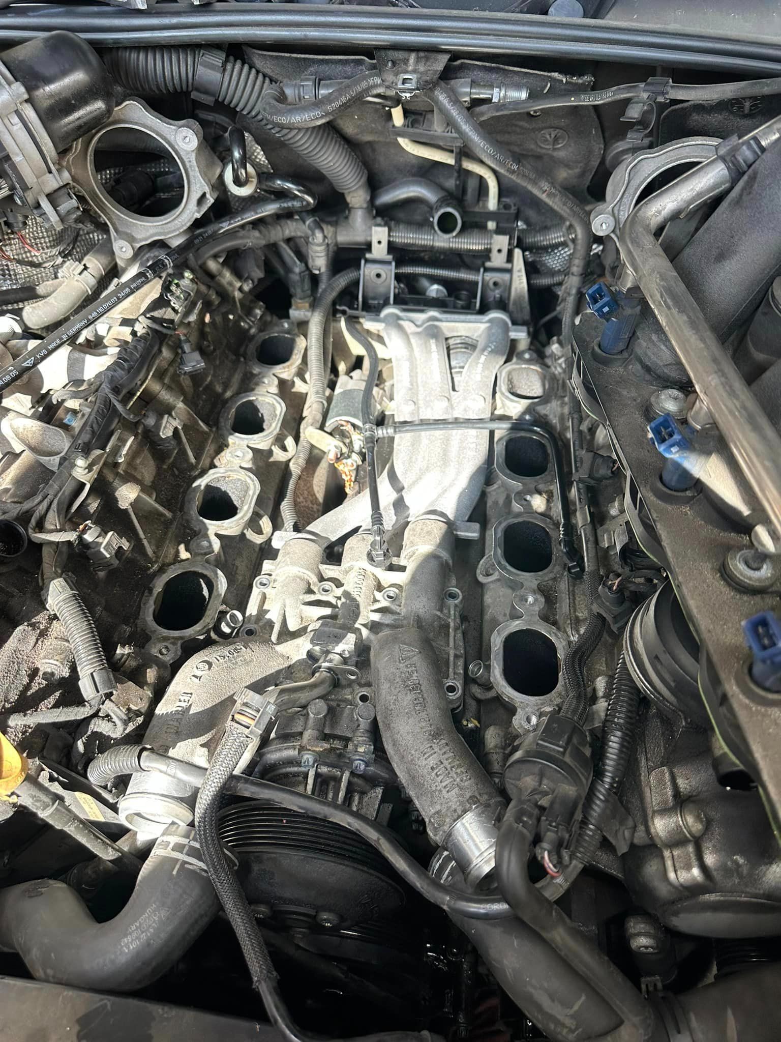 Car engine with intake manifold removed, showing exposed engine components and wiring.
