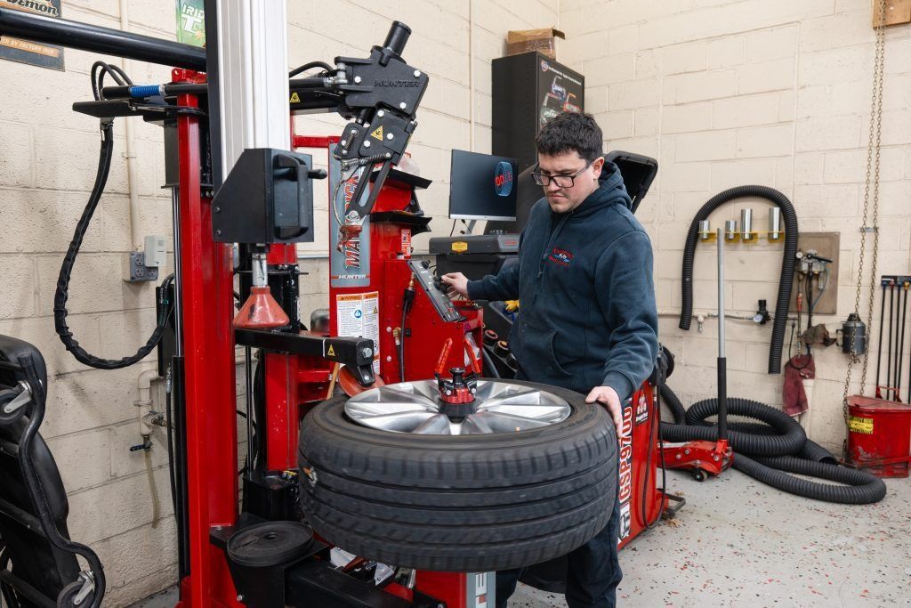 Man using tire machine in auto shop, placing tire onto the device.