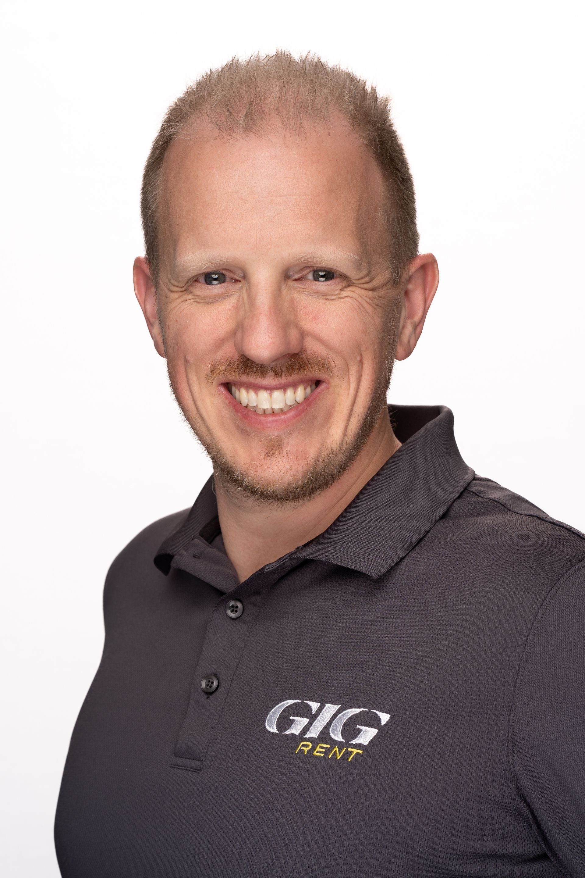 A man with a beard is smiling for the camera while wearing a black shirt.
