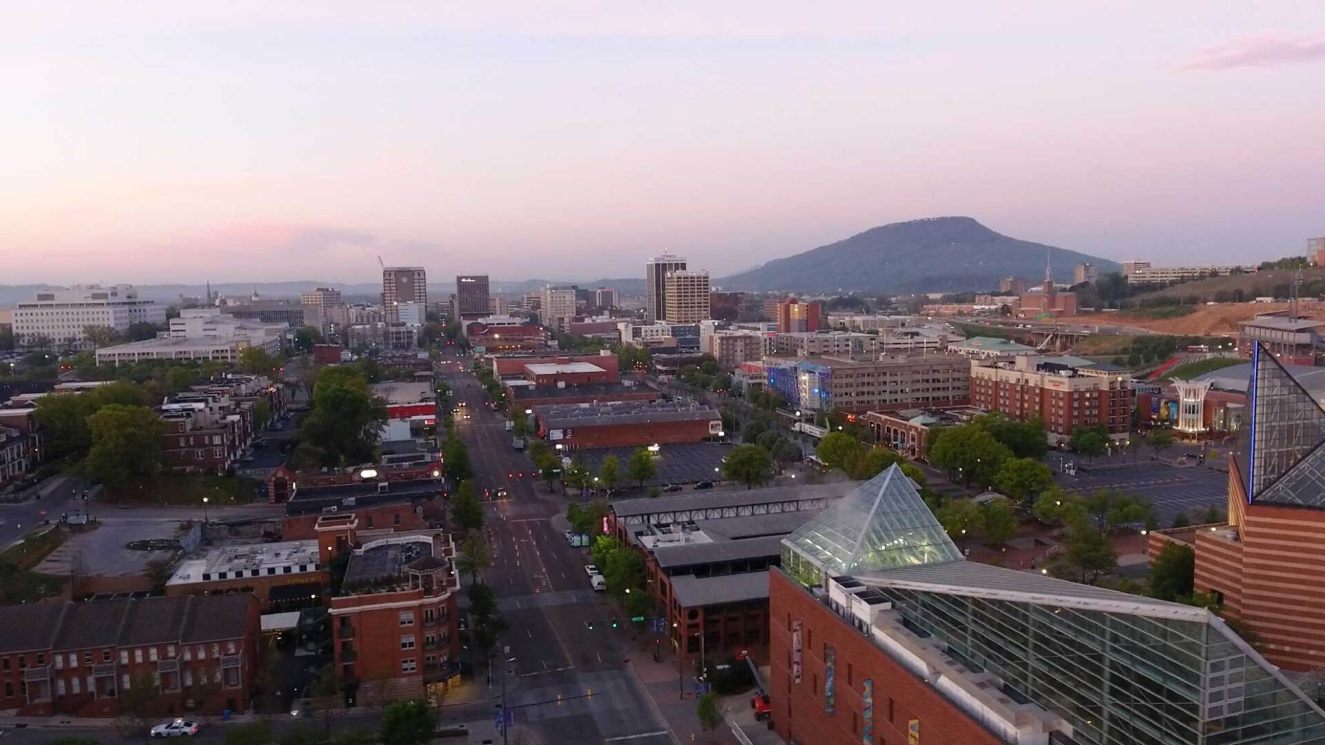 An aerial view of a city at sunset with a mountain in the background.