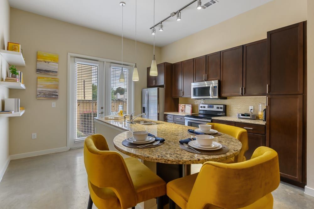 Apartment dining room with a round table and yellow chairs at The 704 in South Lamar Austin, TX.
