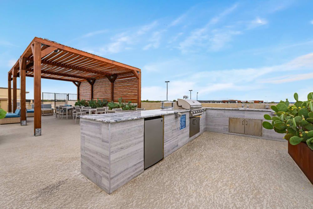 A large outdoor kitchen with a grill and a pergola at The 704 in Austin TX.