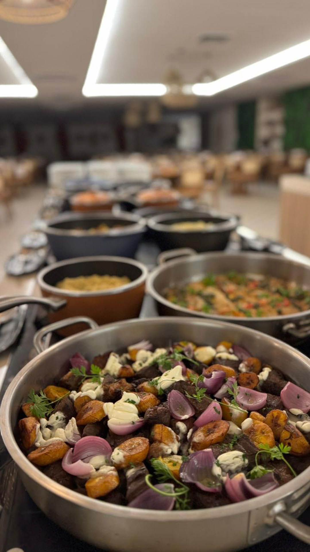 Mesa de buffet com tigelas de saladas e legumes variados em uma área de refeições de restaurante bem iluminada.