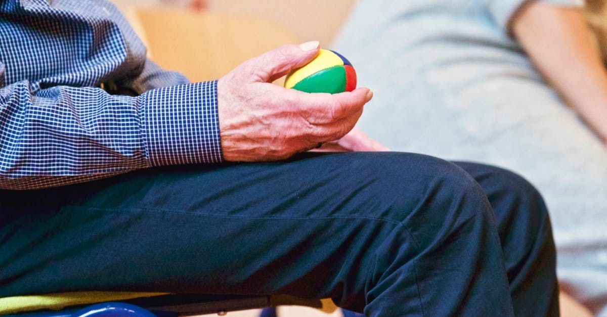 A man is sitting on a chair holding a ball in his hand.