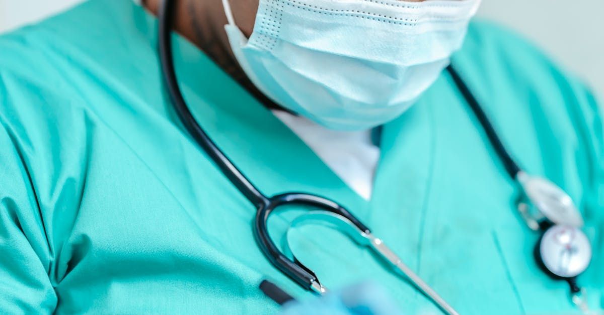 A nurse wearing a mask and stethoscope is holding a syringe.