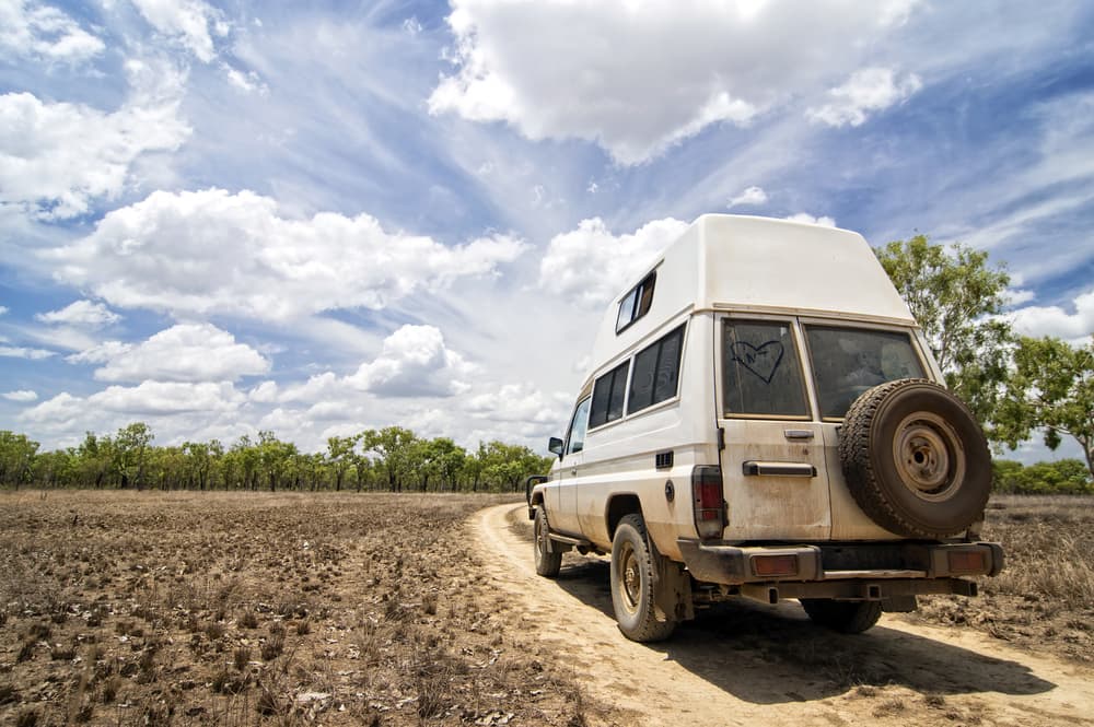 A White Van is Parked on a Dirt Road in the Middle of a Field — Howards Professional Driving School In Gordonvale, QLD