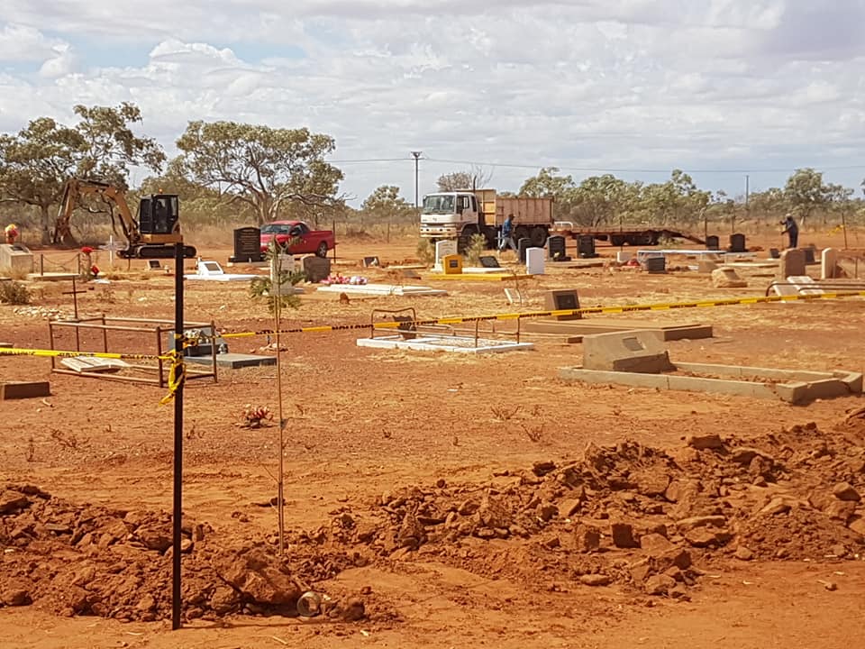 A dusty cemetery with gravestones, some with yellow caution tape.