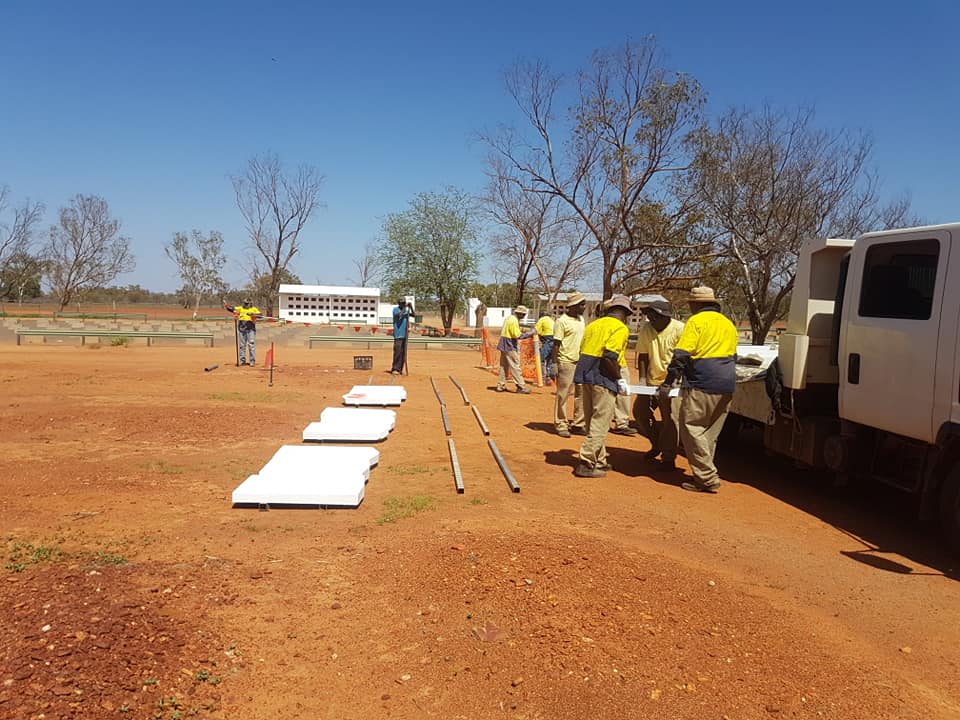 Workers in yellow shirts assemble equipment.