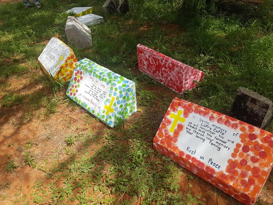 Colorful painted memorial stones arranged on grassy ground.