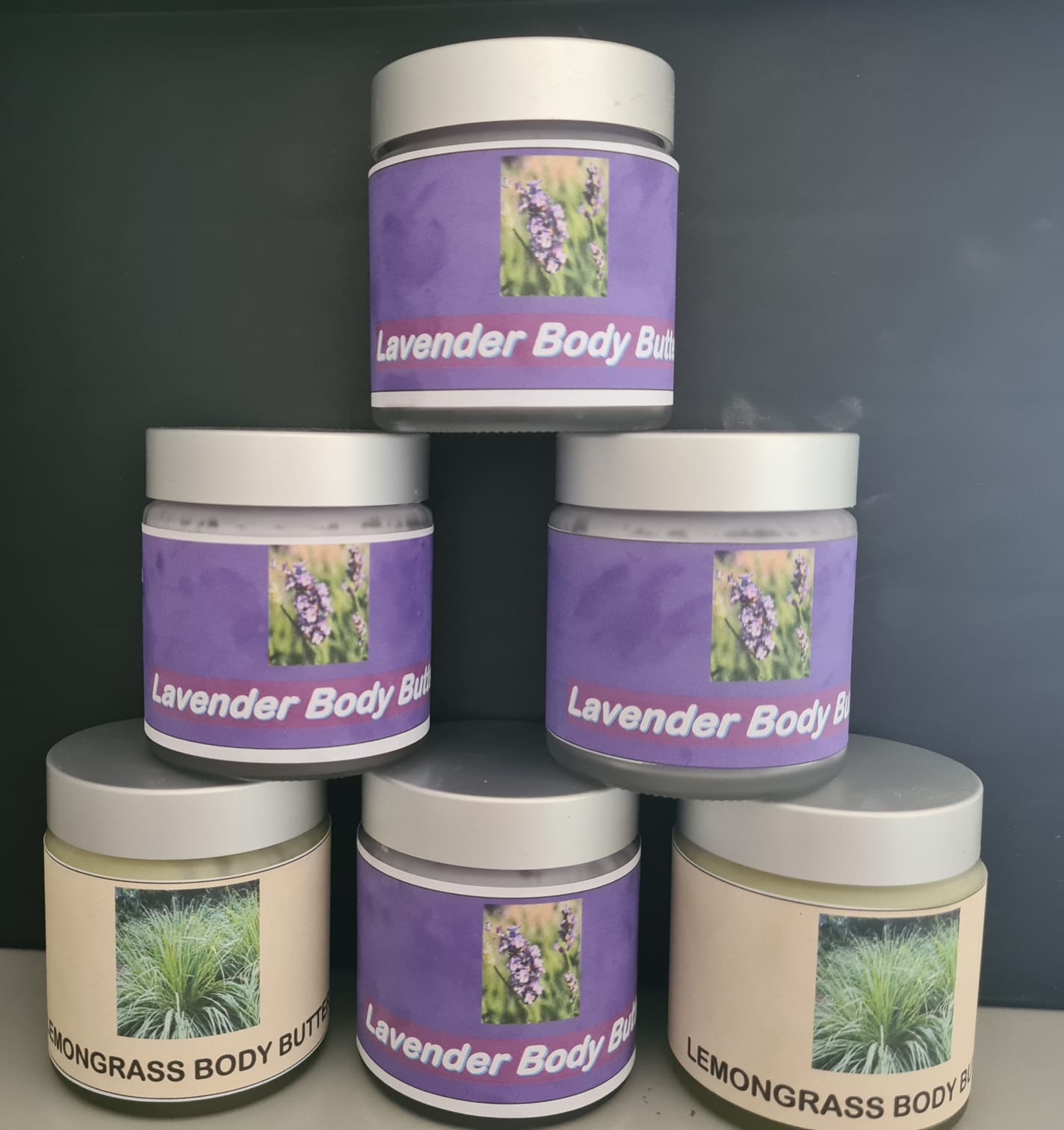 Six jars of body butter, stacked pyramid-style. Five are labeled