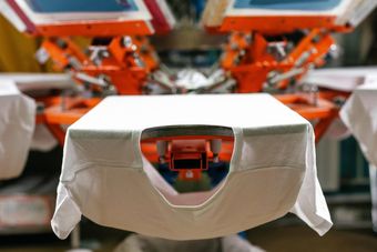 Close-up of a white garment on a press machine with orange components in the background