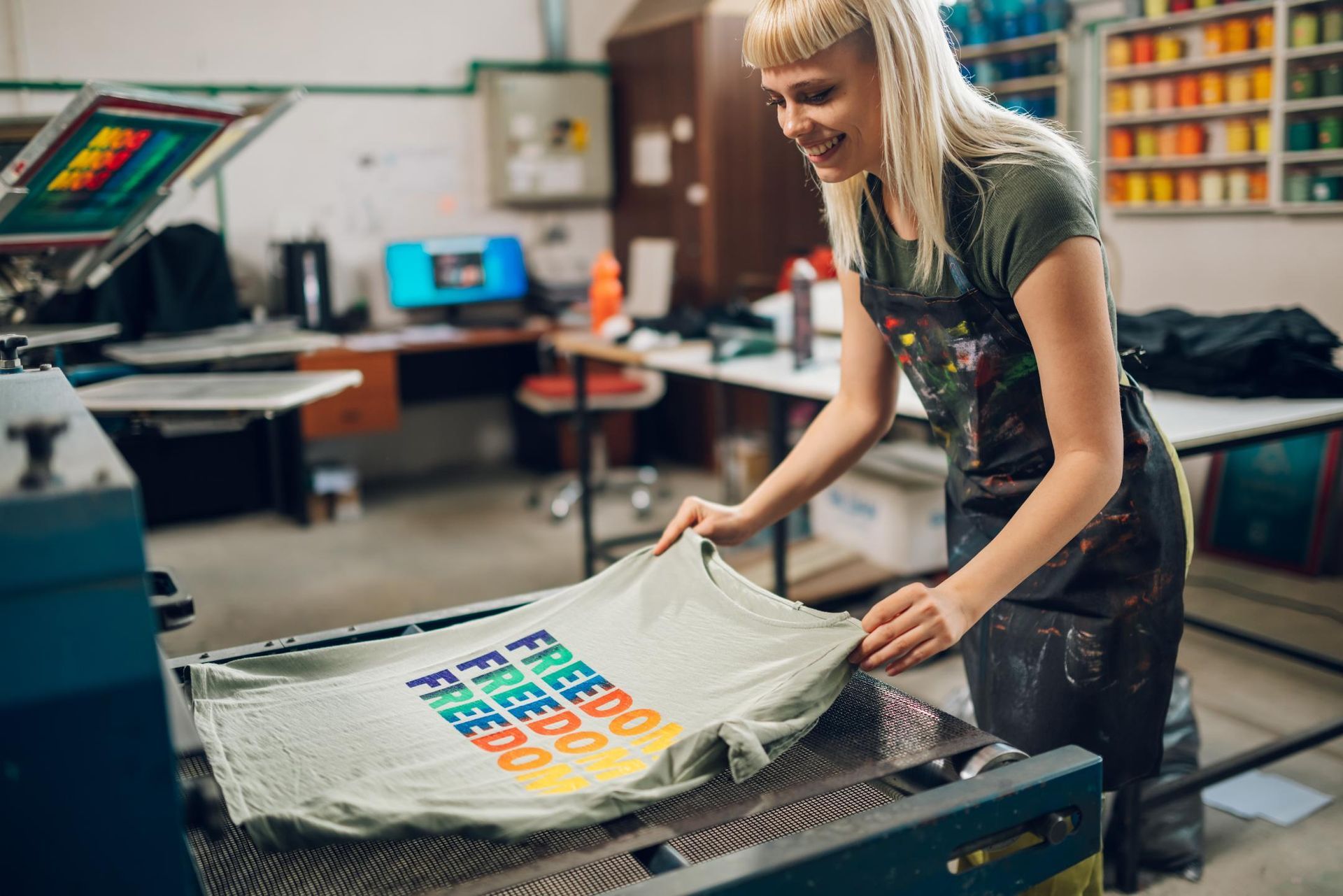 Woman screen-printing a colorful T-shirt in a workshop