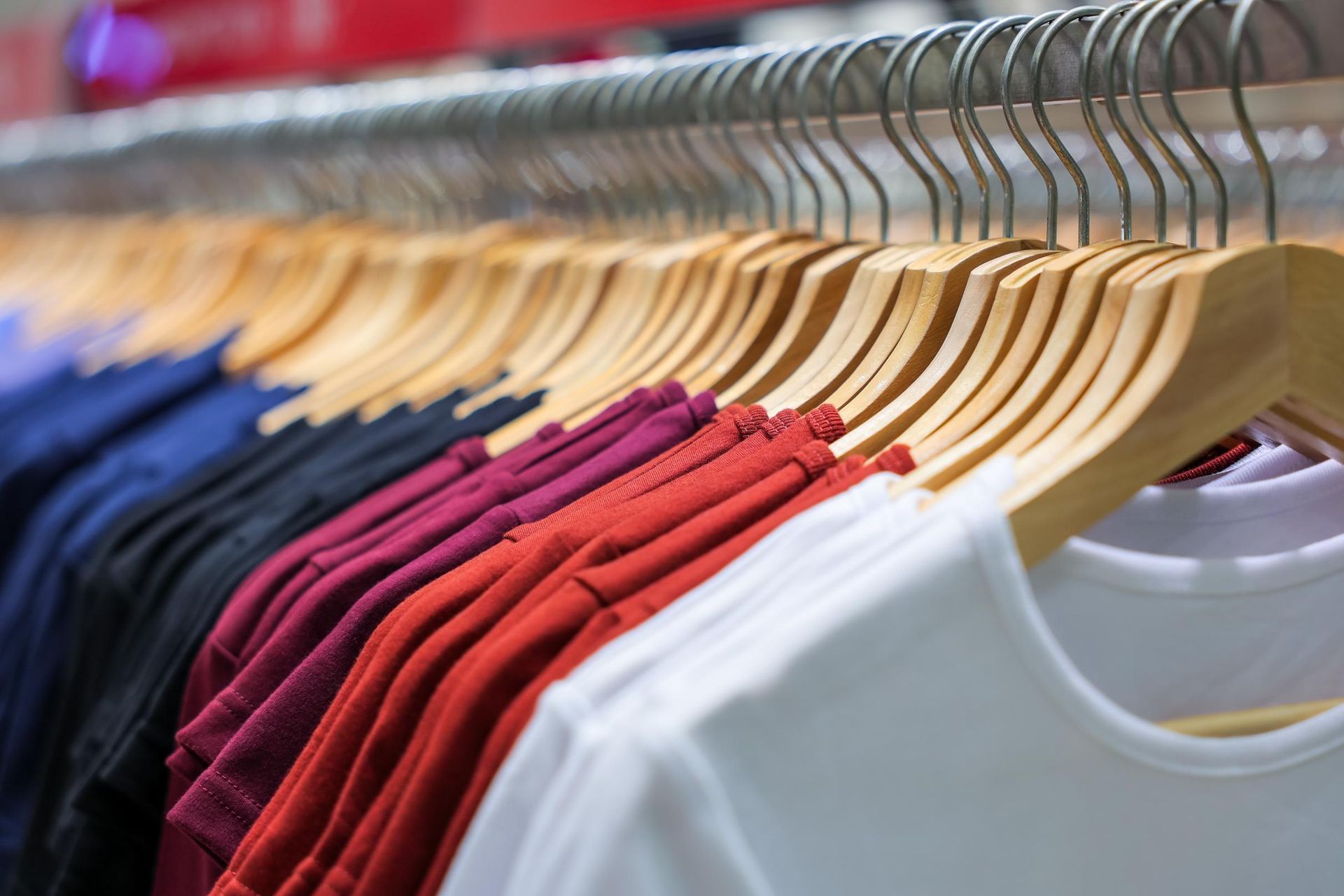 Colorful T-shirts on wooden hangers in a clothing store rack