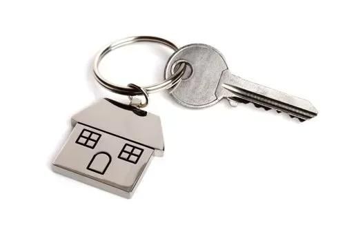 House-shaped keychain attached to a silver key on a white background