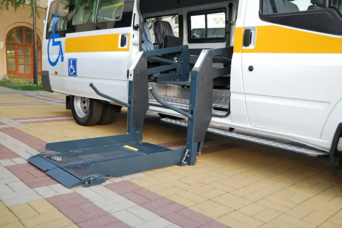 A white van with a handicap lift is parked on a brick sidewalk.