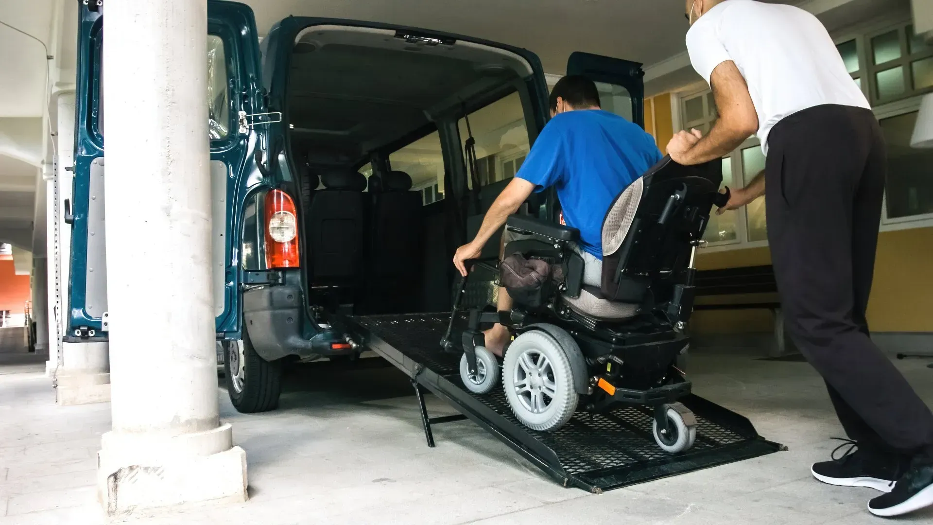 A man is pushing a man in a wheelchair into a van.
