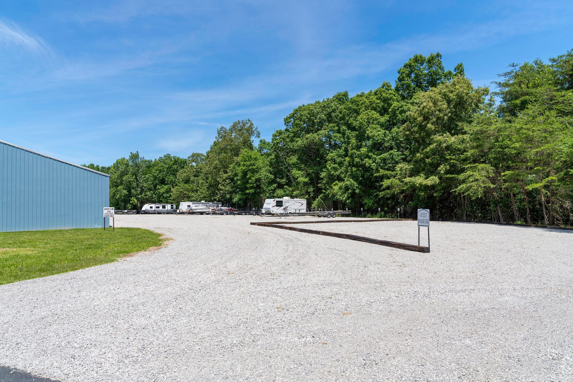 A gravel lot with a building in the background and trees in the background.