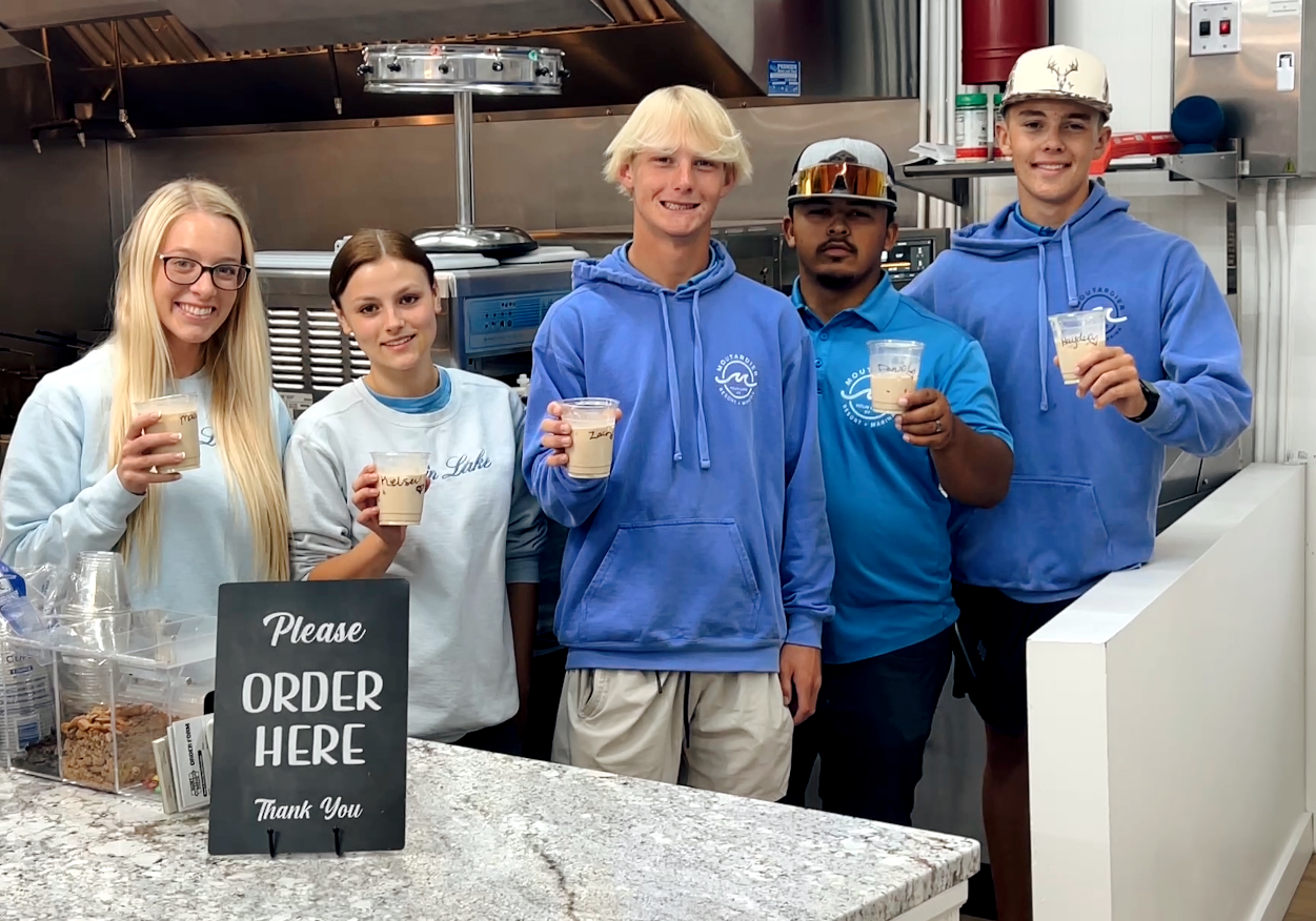 A group of people are standing in a kitchen.