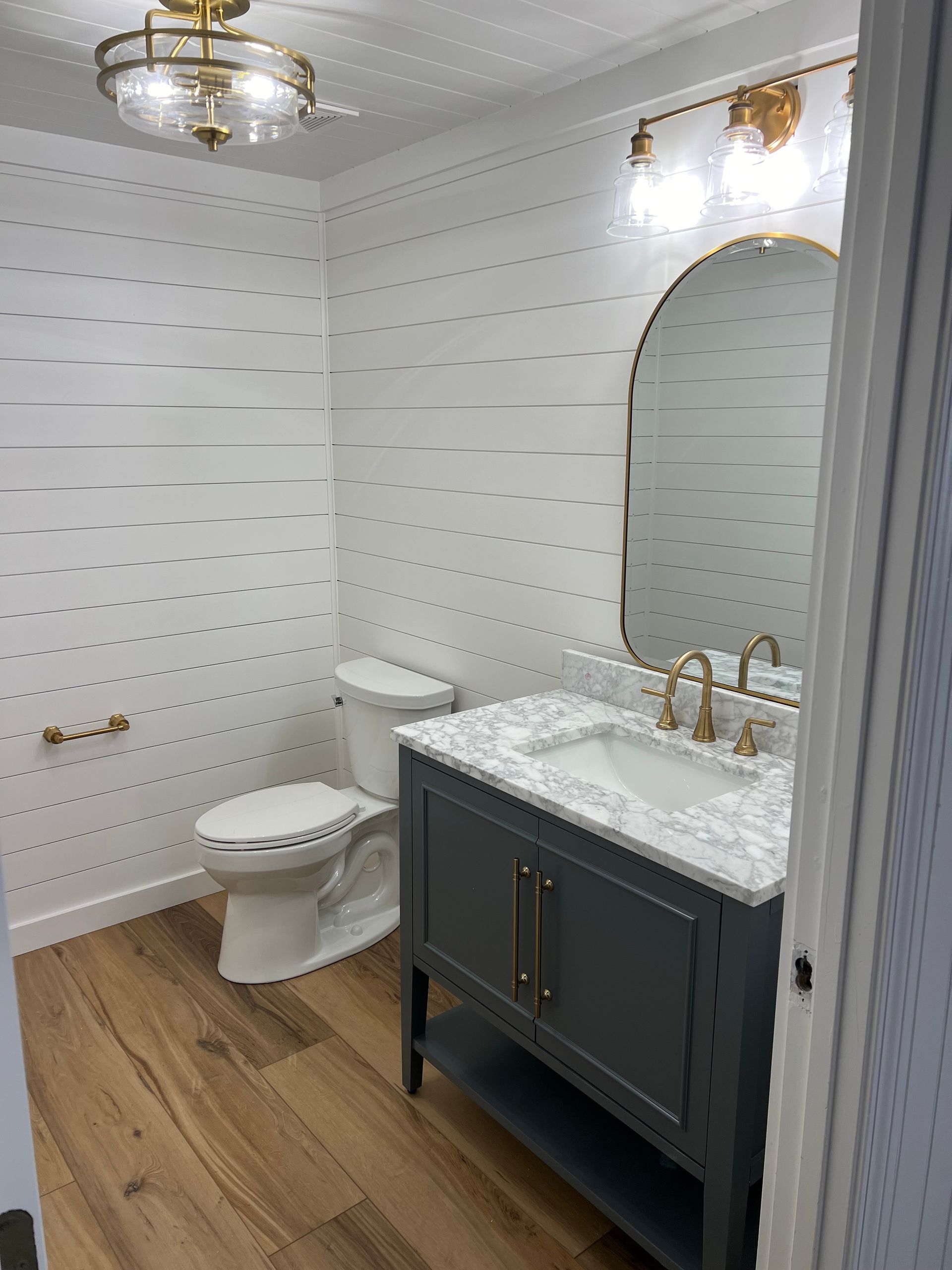 A bathroom with a toilet , sink and mirror.
